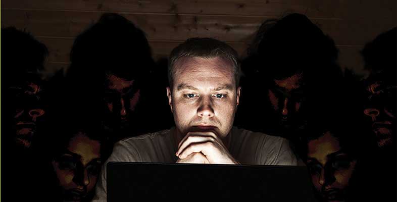 Image of man on laptop surrounded by people in shadow