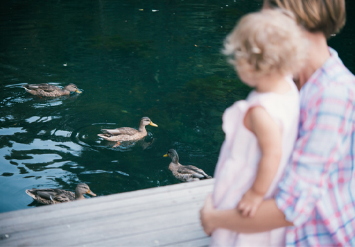 This is a photograph of a woman and a child at a duck pond.