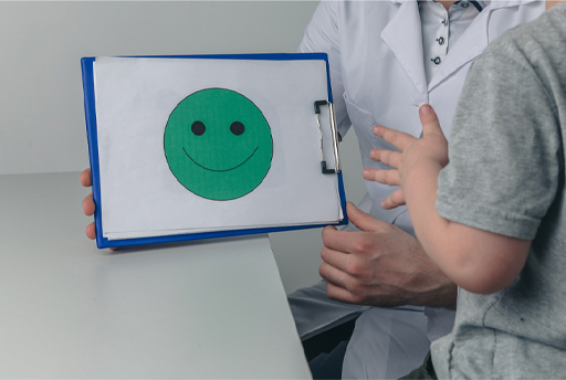 A photograph of a therapist holding a clipboard with a drawing of a smiley face on it.