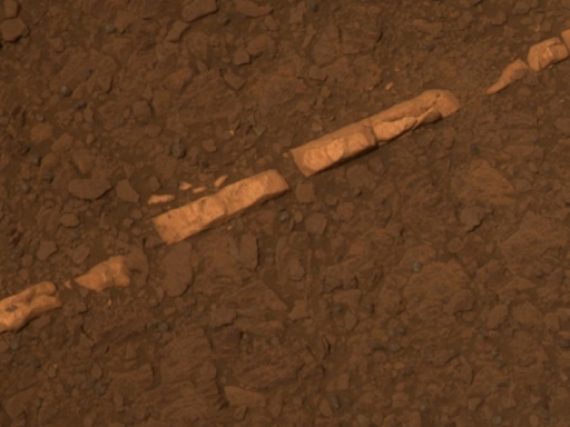 This figure is a photograph taken by the Opportunity rover of a rock outcrop. The rock is brown in colour, but a band of white goes across the image from bottom left to top right. The band is broken in places, interrupted by brown.
