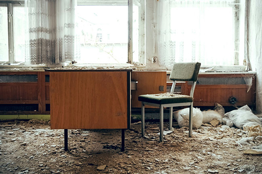 An empty office, with rubble on the floor and desk.