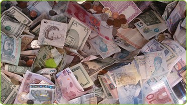 An image of a pile of monetary notes of different currencies and denominations.