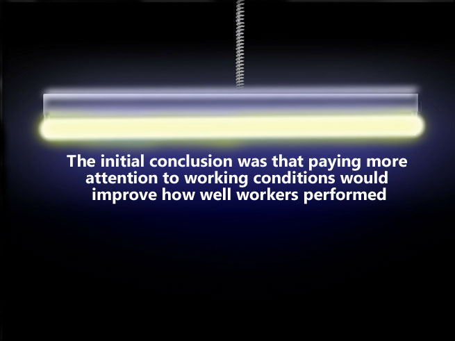 A bright yellow halogen bar light is positioned horizontally across the top of a black rectangular background. Text below is written in white and says "the initial conclusion was that paying more attention to working conditions would improve how well workers performed",