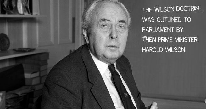 Black and white photograph of Harold Wilson sat looking at the camera in a modest office-like setting. White text saying "the Wilson doctrine was outline to Parliament by then Prime Minister Harold Wilson" is on the right side of the picture.