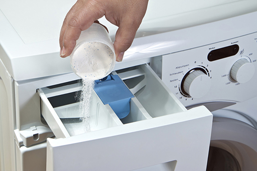 An image of washing powder being poured into a washing machine.