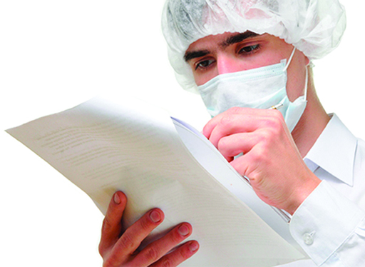 A photo of a lab worker reading a piece of paper and making notes onto it.