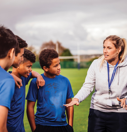 A photograph of a female coach speaking to four boys.