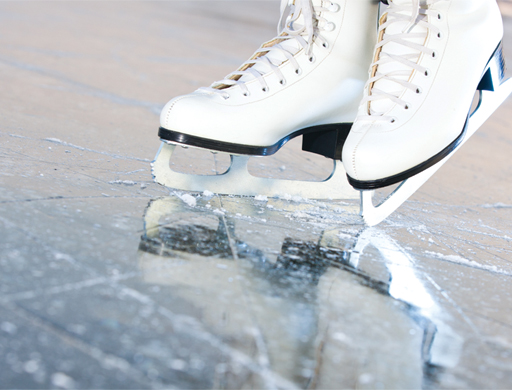 A close up of ice skates on an ice rink.