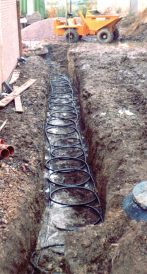 Evaporator pipes being laid in a trench for a ground-source heat pump