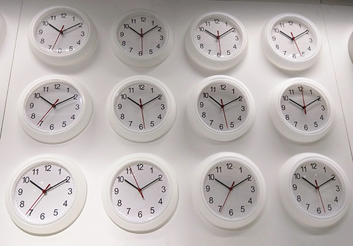 Array of clocks mounted on the wall of a homeware store, all showing the same time.