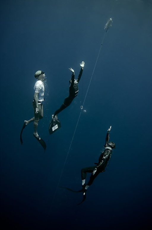 A colour photograph of two divers coming to the surface in the Caribbean.