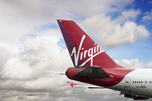 The red tail of a Virgin plane against a blue sky with white clouds