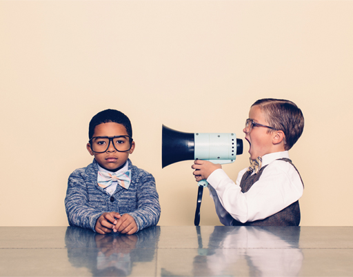 A photograph of two young boys: one is trying to speak to the other through a megaphone.