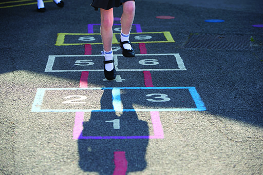 A photograph of a child playing hopscotch.