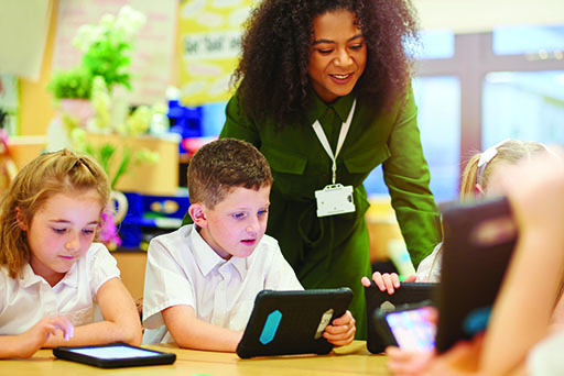 An image of a woman with a group of children who are all holding smart devices.