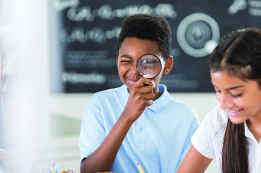 A photograph of a child looking through a magnifying glass.