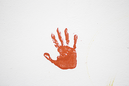 An orange handprint on a white wall