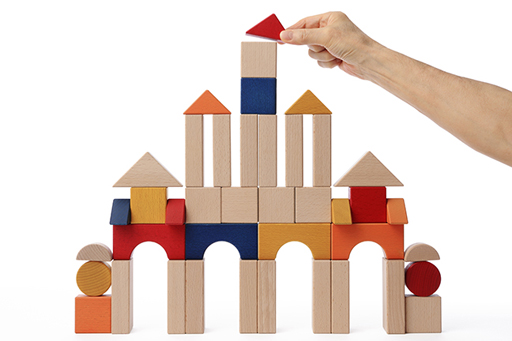 An image of someone constructing a building from wooden blocks