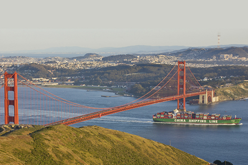 An image of a China Shipping Lane cargo ship passing under the San Francisco bridge