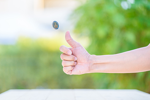 A photo of a hand flipping a coin.