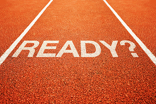 The single lane of a bright orange running track has the word ‘ready?’ written on it in white.