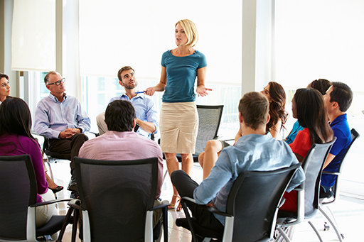 A meeting with a woman standing and talking to the group