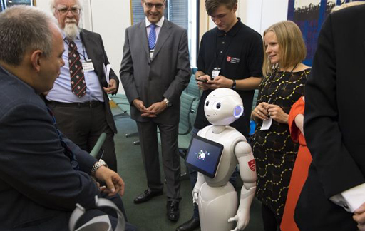 Pepper, the robot, surrounded by a number of people, 'gives evidence in Parliament'.