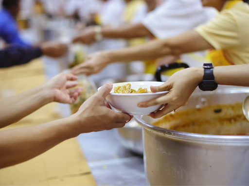 Picture of hands holding out food to other hands who receive the food.