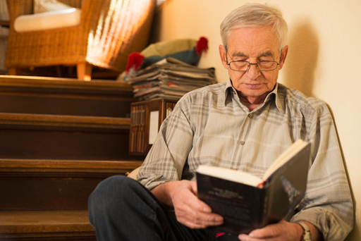 Man sitting on a set of stairs reading a book.