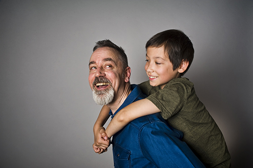 This is a photograph of a man giving a young boy a piggy back.