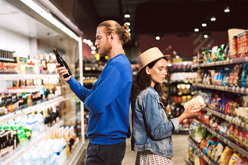 The figure is a photo of a young male and female back-to-back in a supermarket contemplating possible purchases.