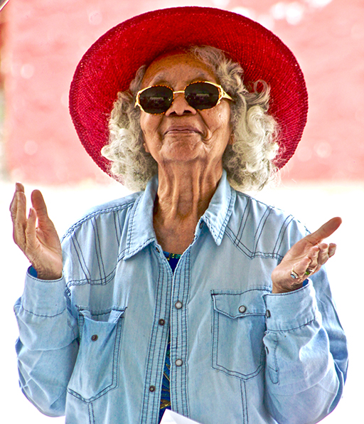 The figure is a photo of a woman, probably in her 60s or 70s, wearing a red sun hat and sunglasses. She looks content and relaxed.
