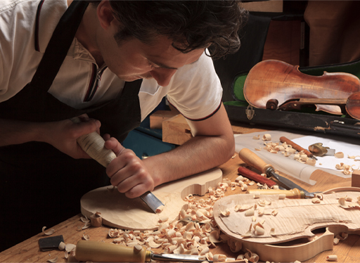 An image of a person carving a violin out of wood