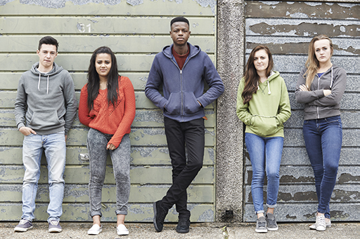 This is a photograph of five young people standing against a wall.