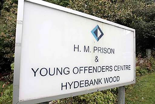 This is a sign outside a prison, which says: H.M. Prison & Young Offenders Centre, Hydebank Wood.