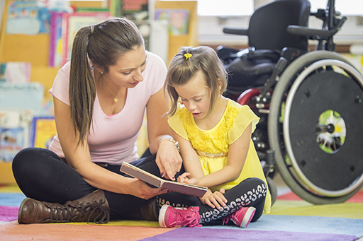 This is a photograph of a woman and a young girl reading together.