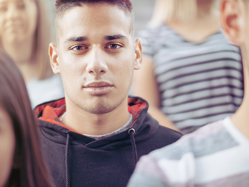 This is a photograph which focuses on a young man while sitting in a crowd.