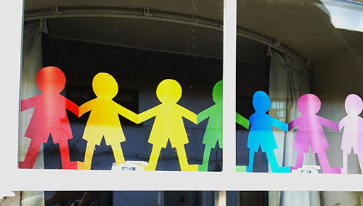 This is a photograph of a chain of paper figures, in the different colours of the rainbow.