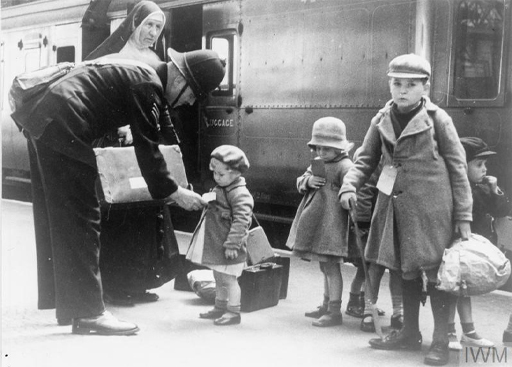 This is a black-and-white photograph of a group of children at a train station.