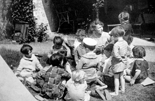 This is a black-and-white photograph of Susan Isaacs sitting with a group of children.
