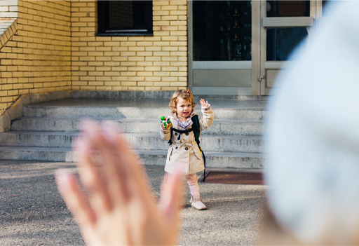 This is a photograph of a parent waving to a child after leaving them at nursery.