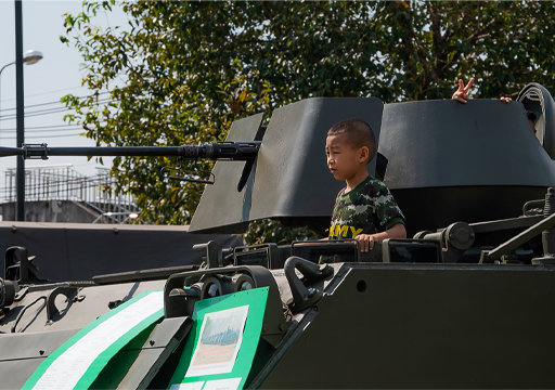 This is a photograph of a child standing on a military tank.