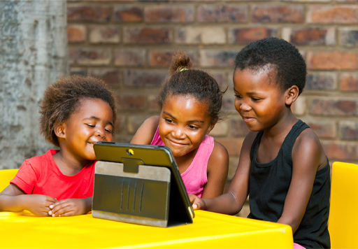This is a photograph of three children using a tablet.