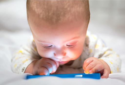 This is a photograph of a baby looking at a smartphone.