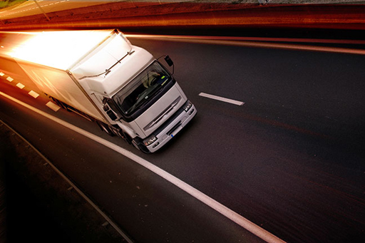 The image is of a lorry driving along an empty road.