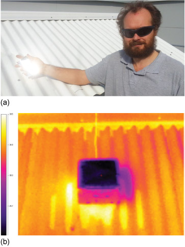 Figure 8a is a photograph that shows Argus Gentle holding new roofing material in his hand. The material is very bright so it looks like the Sun's light is reflecting from it like a mirror. He holds it in front of a white corrugated roof. Figure 8b is a colour coded infrared image that shows the corrugated roof (figure 8a) coloured orange, and the sample of the new material colour coded black, cooler than the roof behind it.