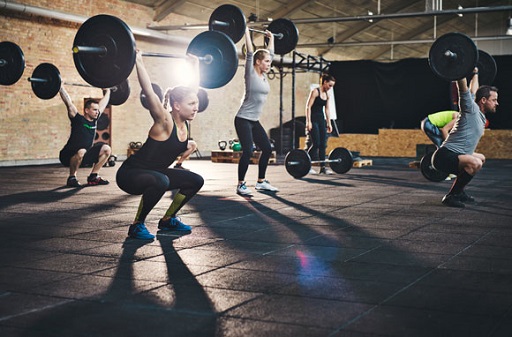Image of men and women performing a snatch lift with a barbell in a gym