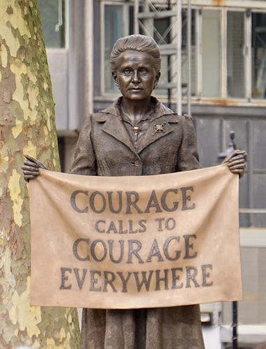A photograph of a bronze statue of suffragette Millicent Fawcett holding a banner with the words ‘Courage calls to courage everywhere’.