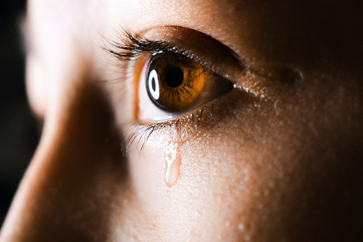 A close up image of someone’s eye with a tear rolling down their cheek.