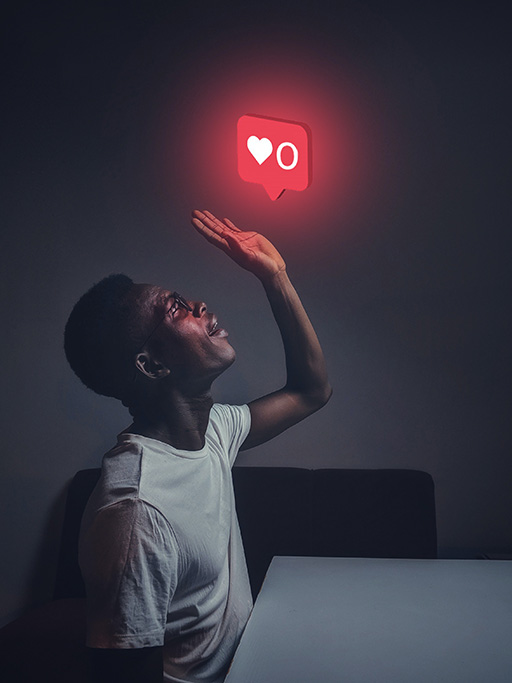 An image of a person sat at a table with one arm in the air, palm up. Above the palm is an image of a love heart, similar to that of a like option found on social media platforms.